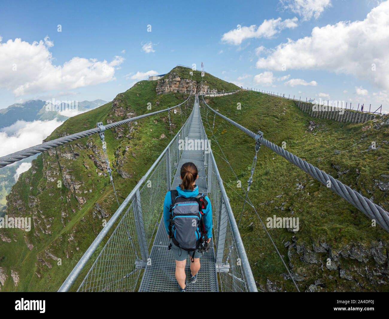 Woman crossing a suspension bridge, Austrian Alps, Bad Gastein, Salzburg, Austria Stock Photo