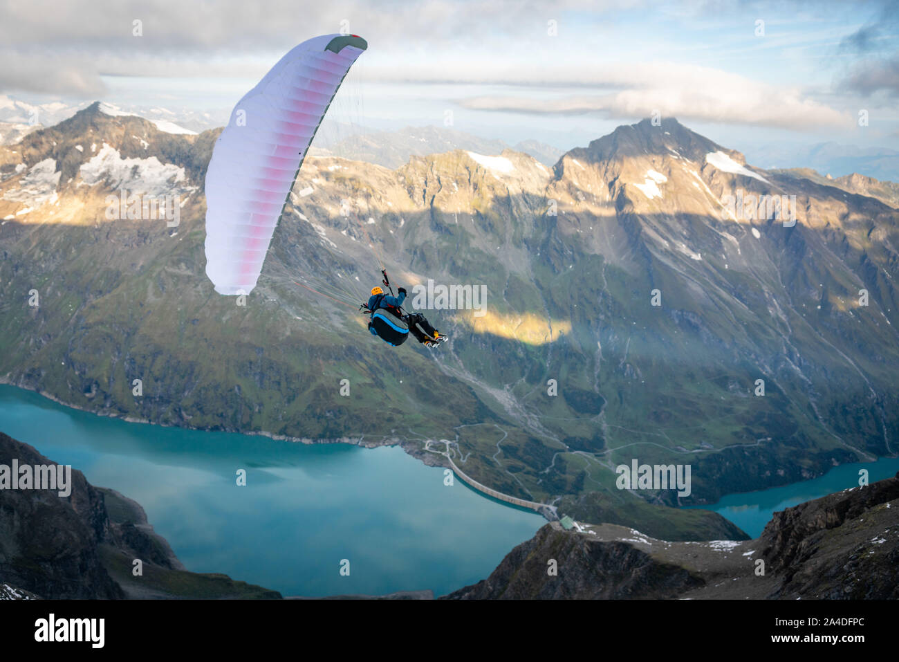 Man paragliding above alpine water reservoirs above Kaprun, Zell am See, Salzburg, Austria Stock Photo