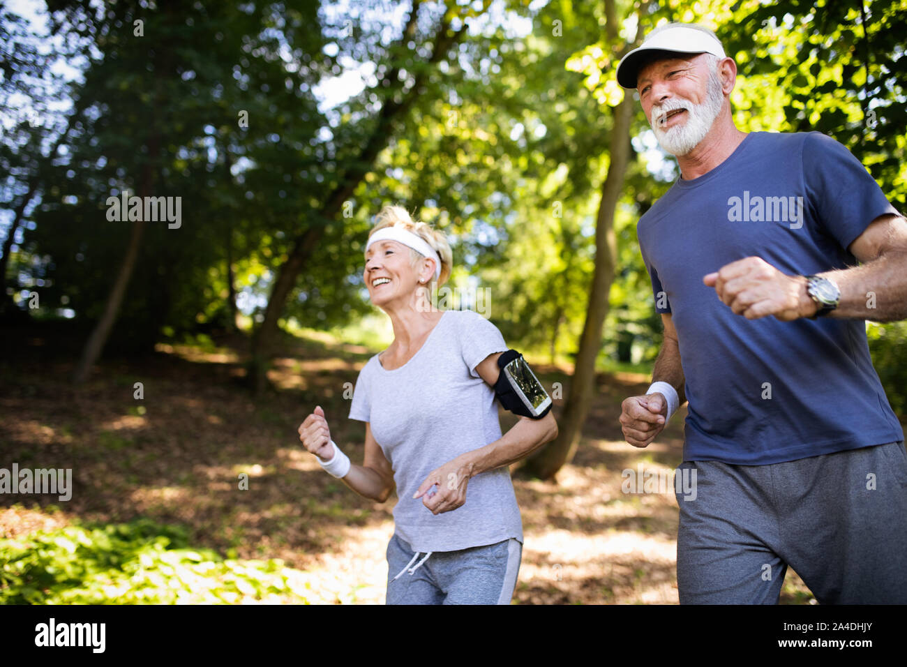 Beautiful senior couple running outside in forest Stock Photo