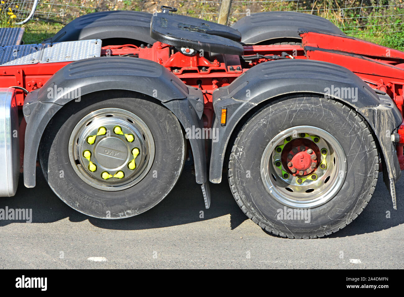 Close up twin axle semi lorry truck one axle lifted to save wear  increase load spread see further info panel also shown loose wheel nut indicators UK Stock Photo