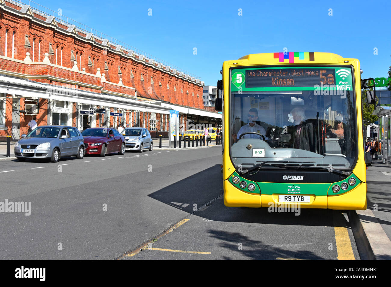 Bournemouth train railway station passengers boarding Yellow buses Optare single decker public transport bus service at stop outside Dorset England UK Stock Photo