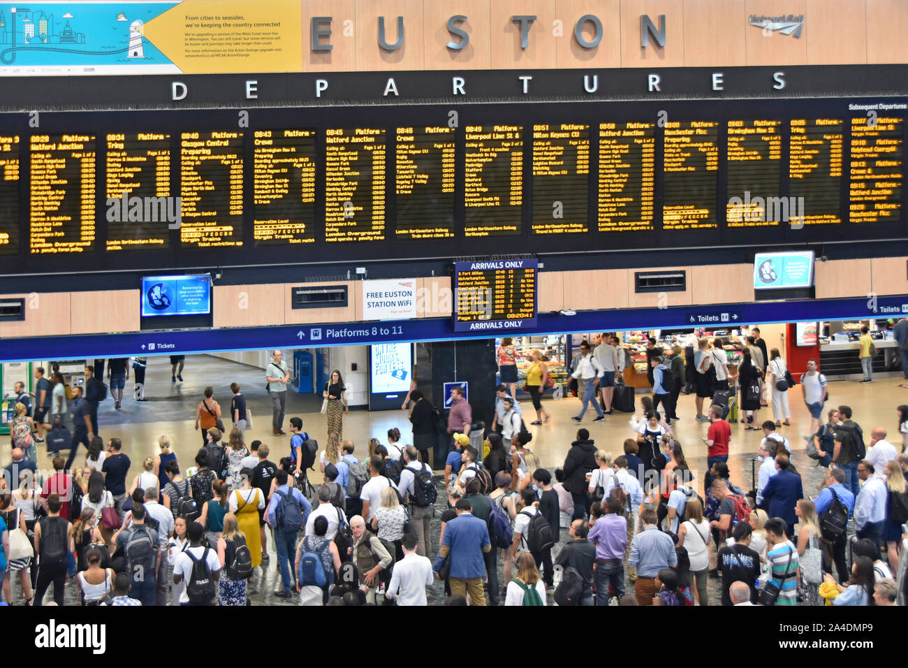 View from above looking down at interior of Euston railway station concourse with passengers viewing train departures & travel information London UK Stock Photo