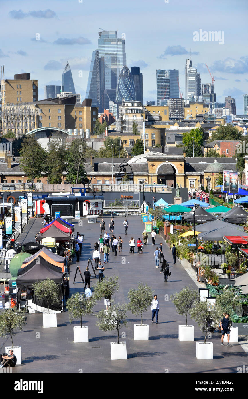 City of London cityscape skyline beyond view looking down on Canary Wharf outdoor alfresco restaurants & street food eateries East London Docklands UK Stock Photo