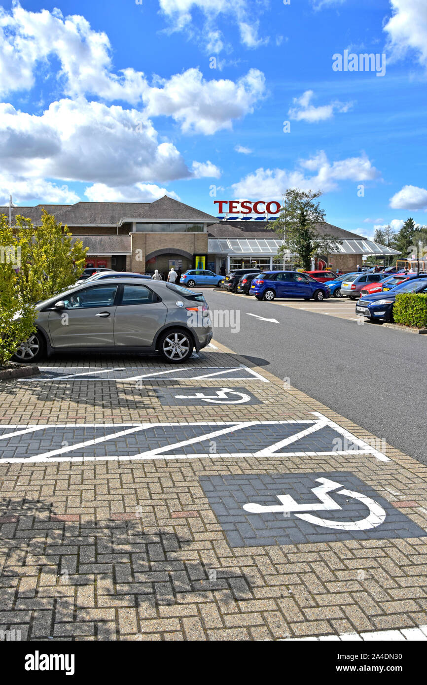 Disabled parking bay icons painted onto block paving in Tesco supermarket customer car park in Ely town centre Cambridgeshire East Anglia England UK Stock Photo