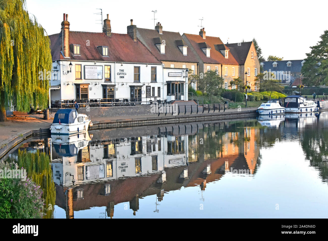 Early morning sunshine clips surroundings of The Cutter Inn pub & Waterside Restaurant reflections in river Great Ouse Ely Cambridgeshire England UK Stock Photo