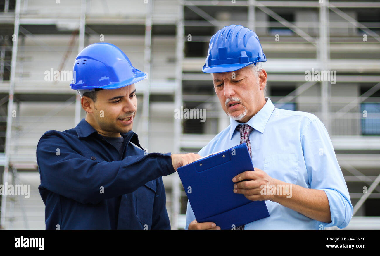 Two architect developers reviewing building plans at construction site Stock Photo