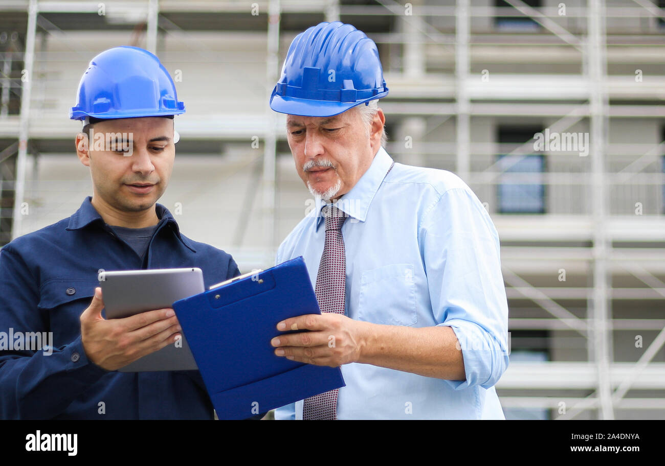Two architect developers reviewing building plans at construction site Stock Photo