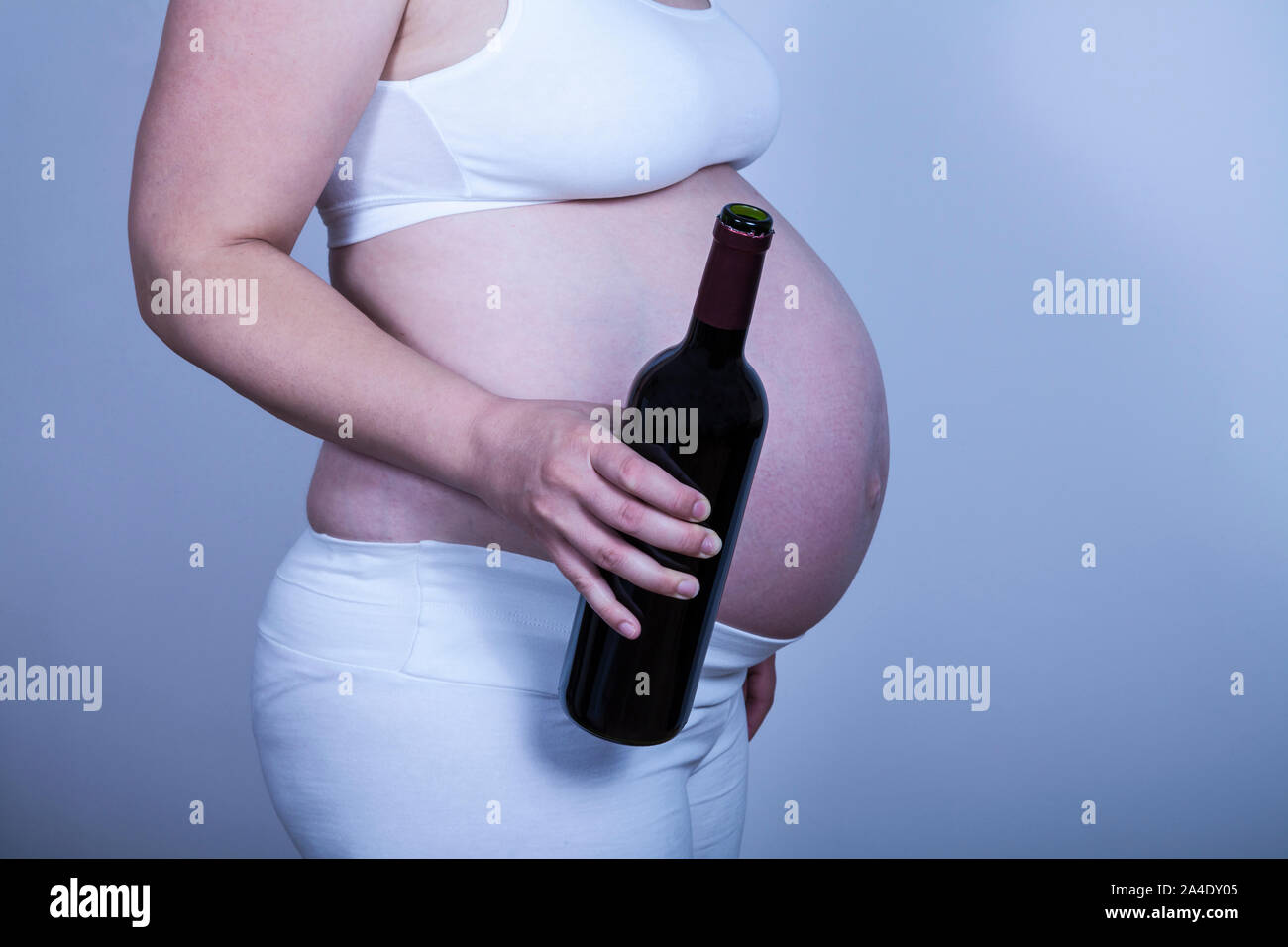 Pregnant woman holdin a bottle of wine in her hand Stock Photo