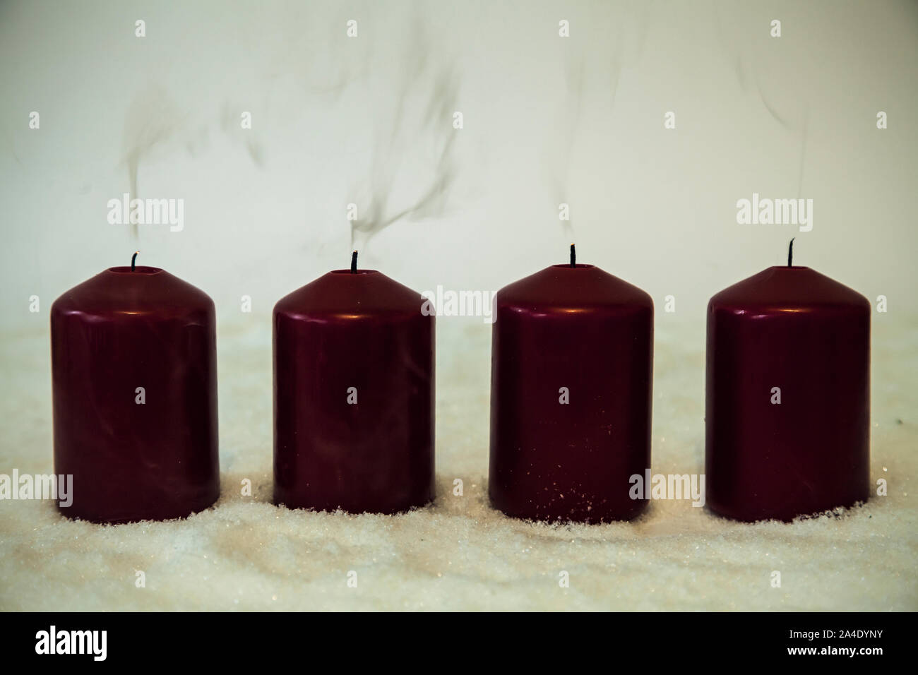 Four smoking candles in snow Stock Photo