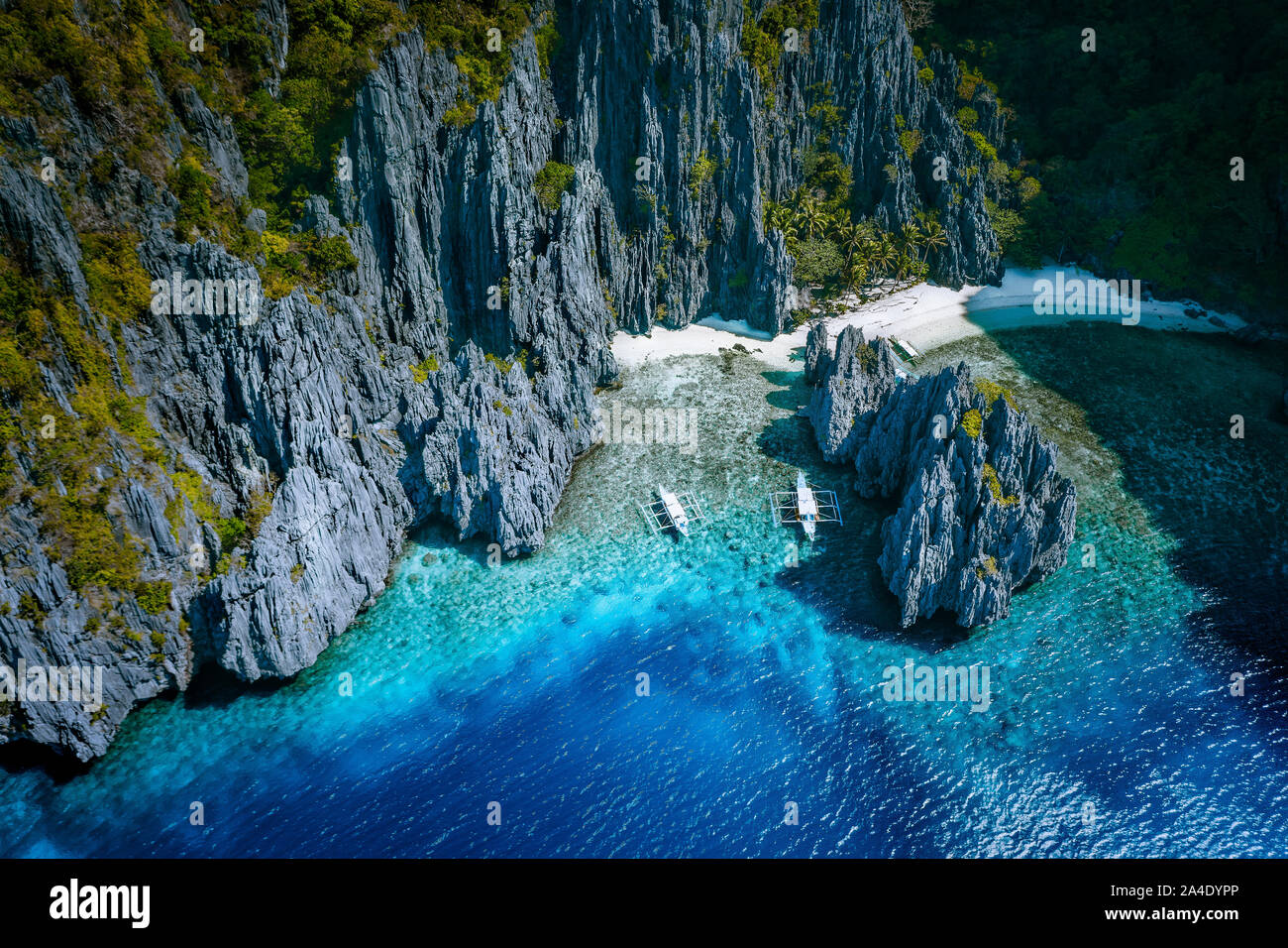 El Nido, Palawan, Philippines. Aerial above view of Secret hidden rocky lagoon beach with tourist banca boats in the cove surrounded by karst scenery Stock Photo
