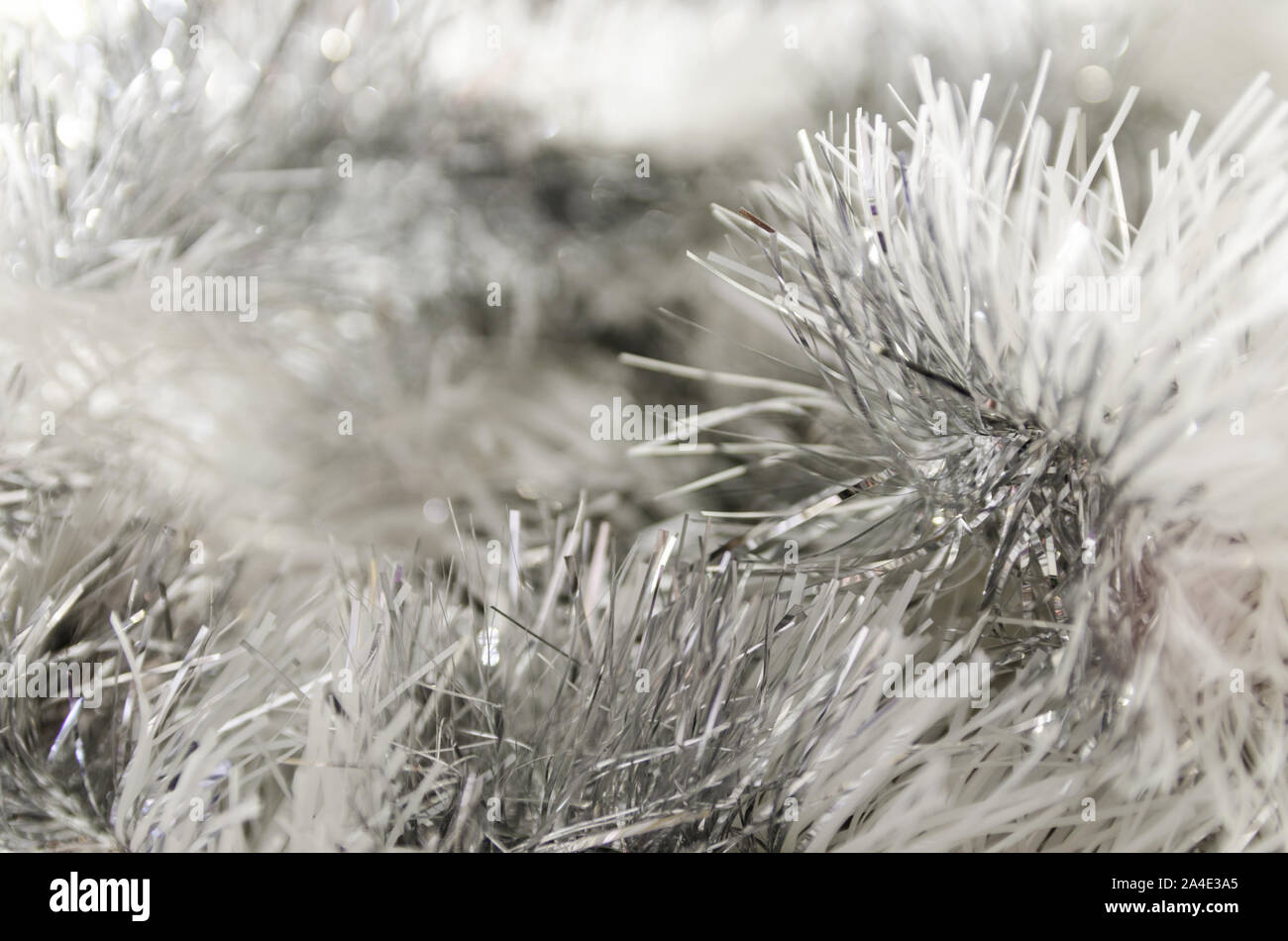 Abstract festive image in silver tone for Christmas or Happy new year background. Close up of hanging holiday tinsel garland. Stock Photo