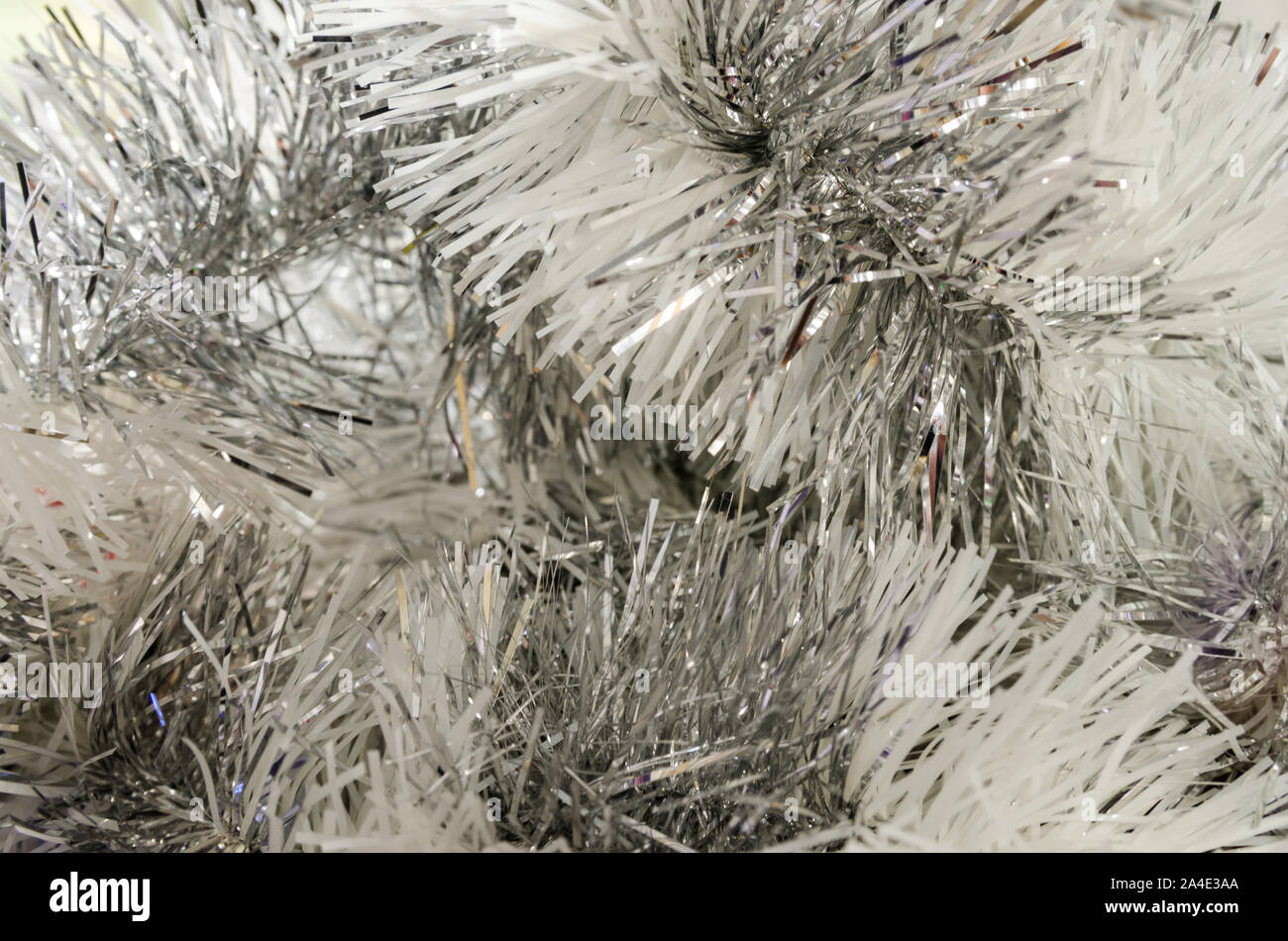 Abstract festive image in silver tone for Christmas or Happy new year background. Close up of hanging holiday tinsel garland. Stock Photo