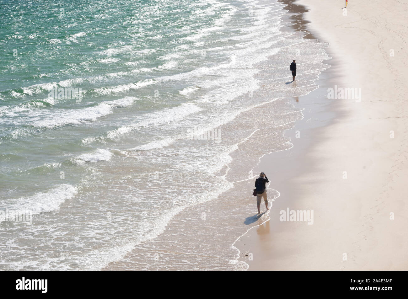 Two people walking along the shore Stock Photo - Alamy