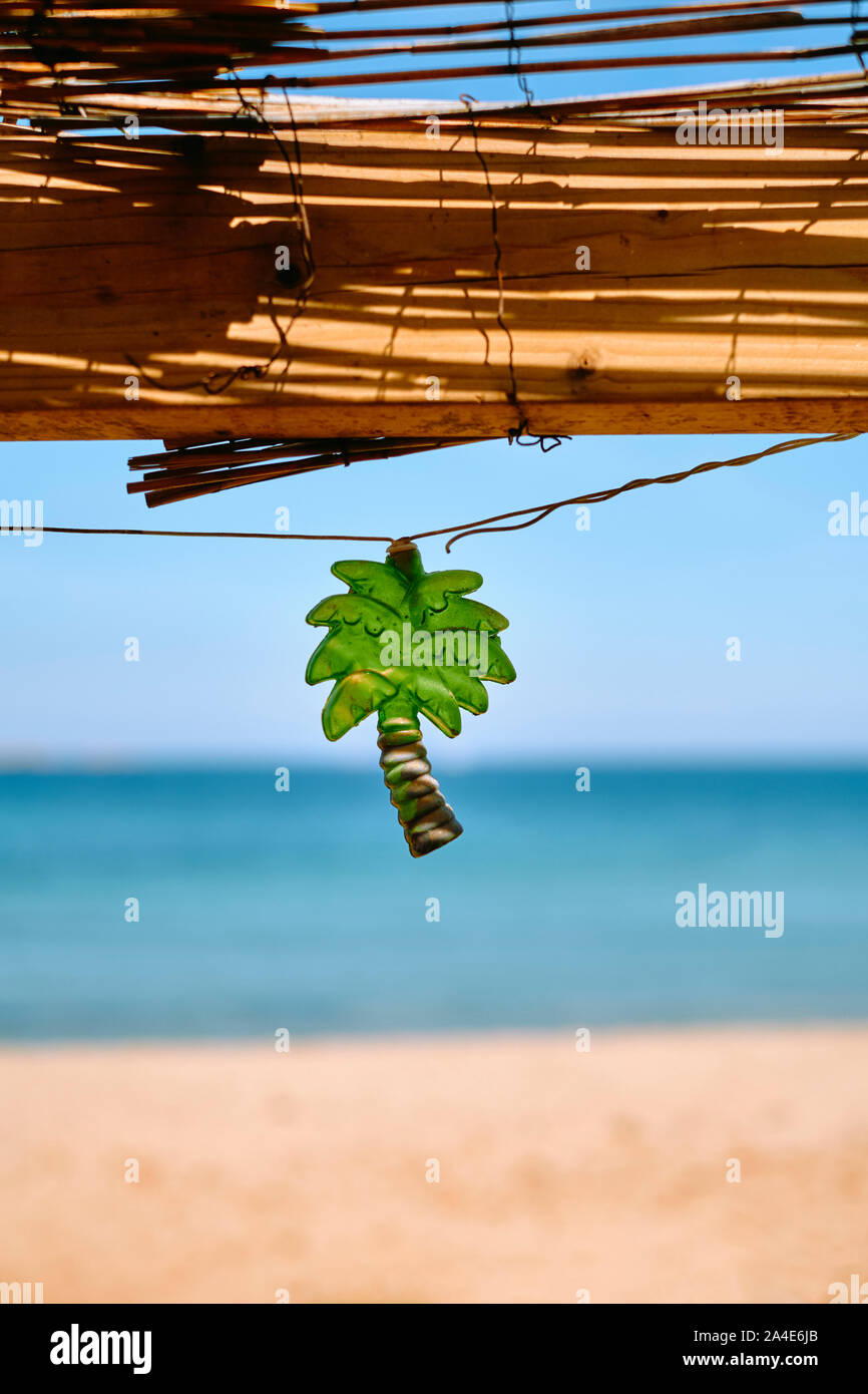 Palm tree shaped string light decorating a rustic beach bar cafe with a blue sea and sky beach background - tropical summer beach holiday symbol Stock Photo