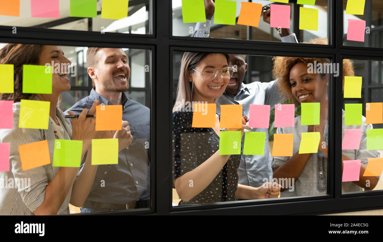 Behind glass wall standing businesspeople celebrating successful