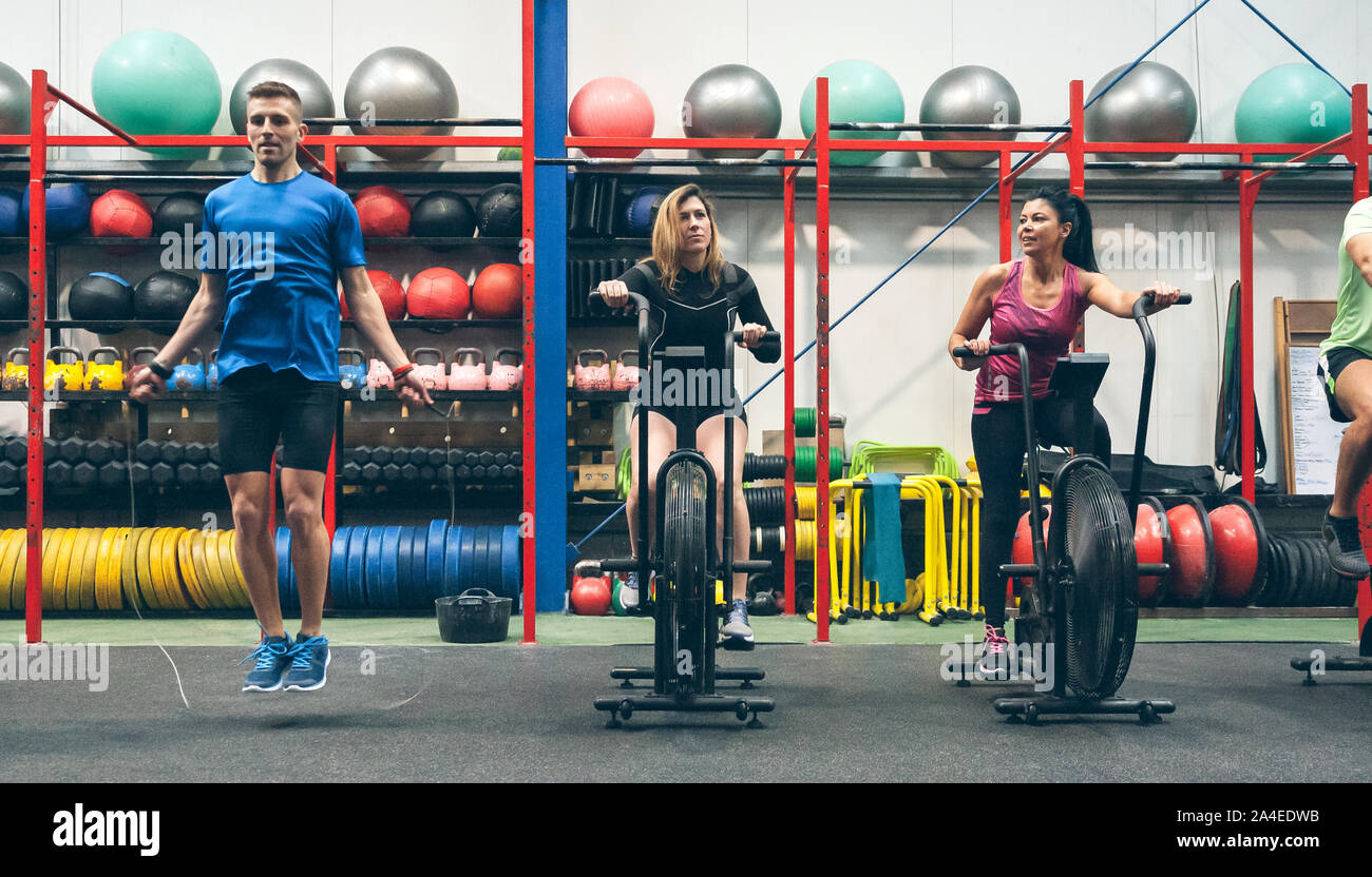 Athletes doing air bike and skipping rope Stock Photo
