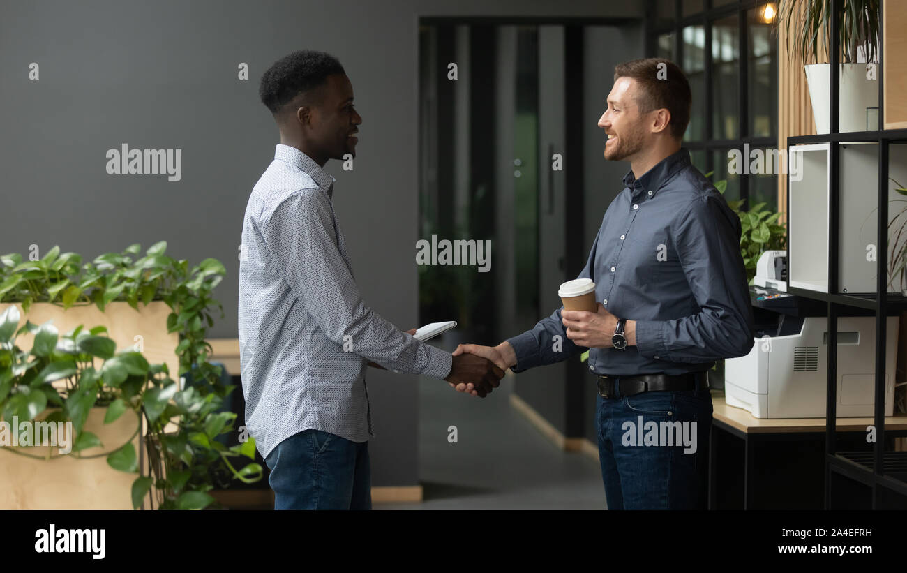 African and caucasian ethnicity colleagues greet together shaking hands Stock Photo