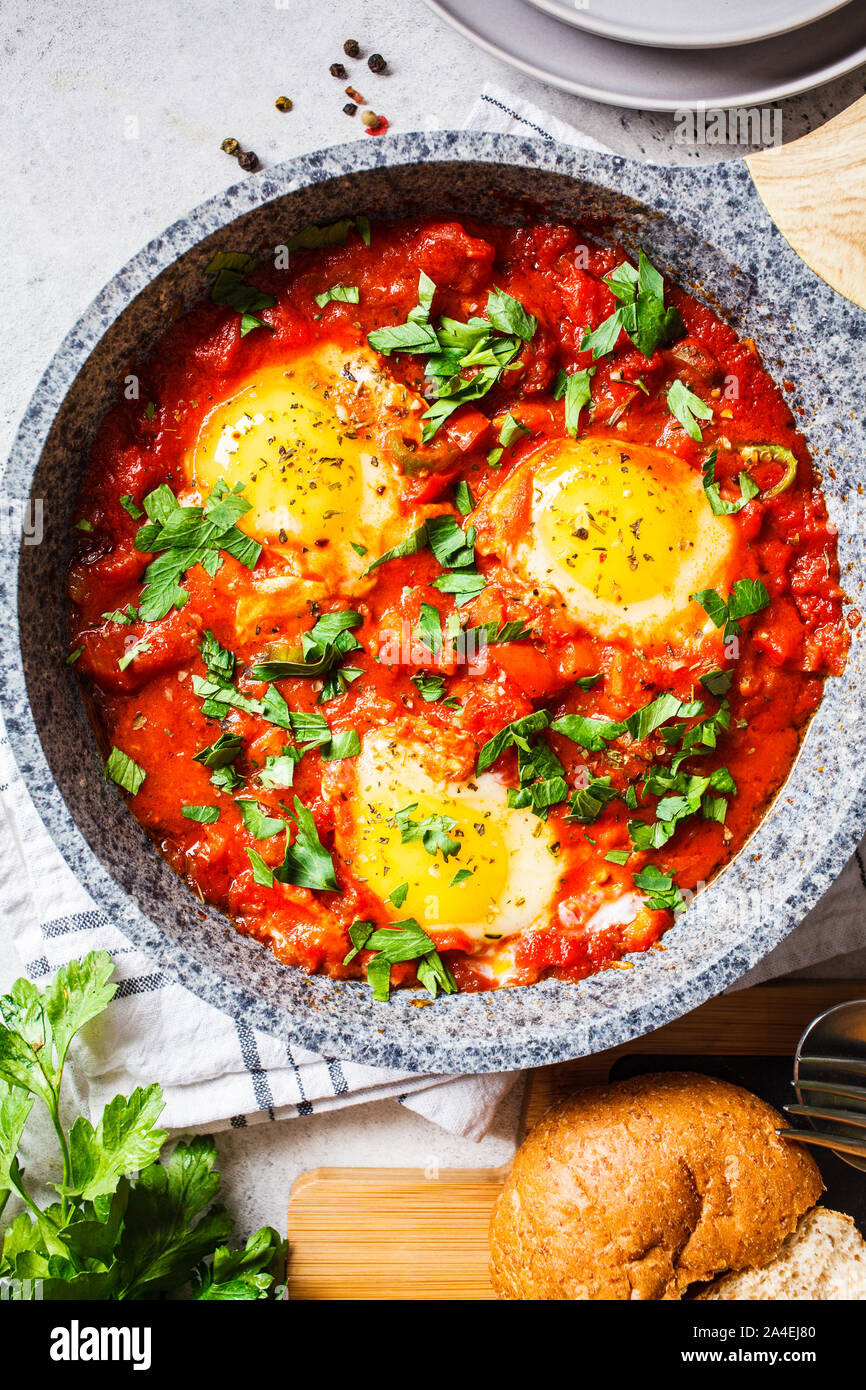 Traditional shakshuka in a pan. Fried eggs in tomato sauce with herbs. Stock Photo