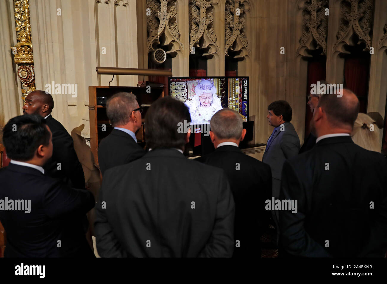 Members of Parliament watch the Queen's Speech on a screen in the Peers