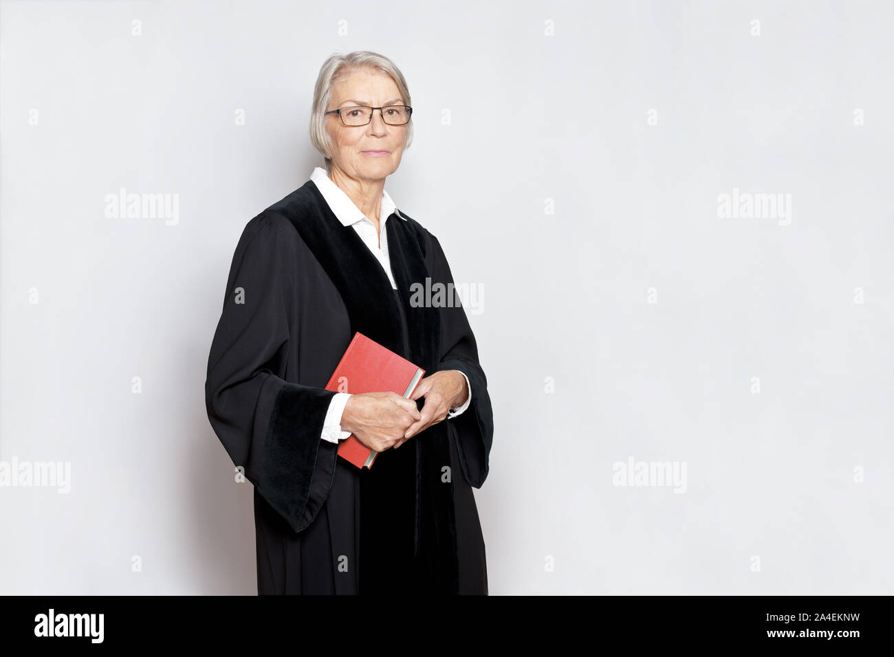 Female jurisdiction concept friendly german judge in a black judge's gown holding a book with