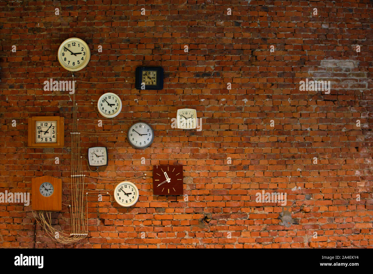 Collection of vintage wall clocks hanging on an old brick wall Stock