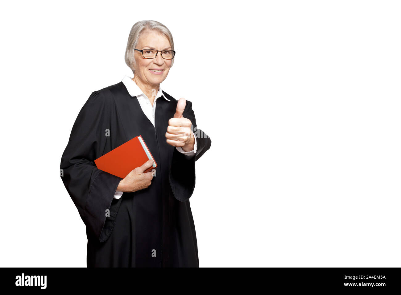 Best legal advice concept: mature woman in a black gown with a law book making the thumb's up sign. Stock Photo