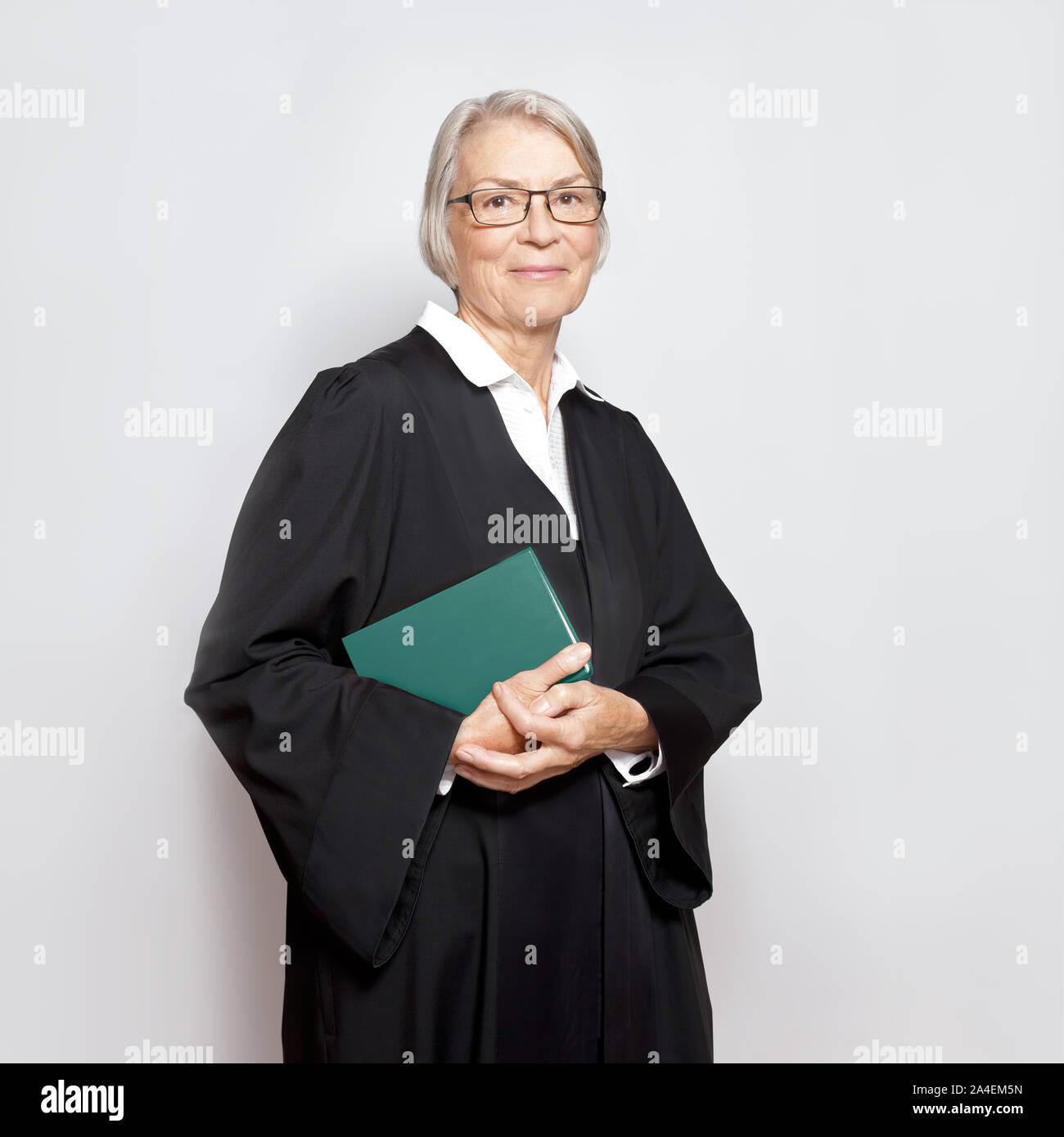 Best legal advice concept: portrait of a friendly smiling mature judge with law book in judicial court dress Stock Photo