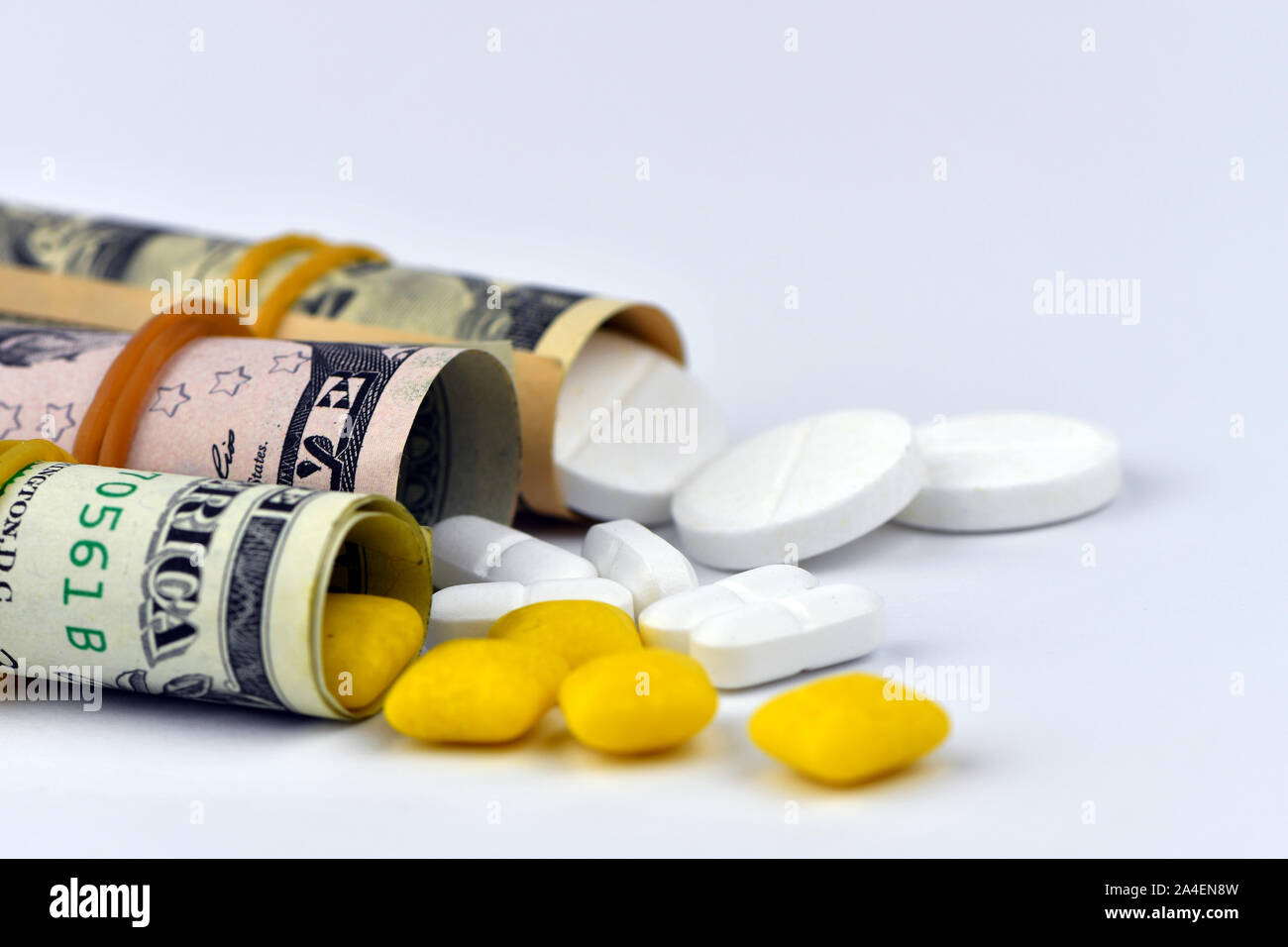 Dollar rolled up with pills flowing out isolated on white background