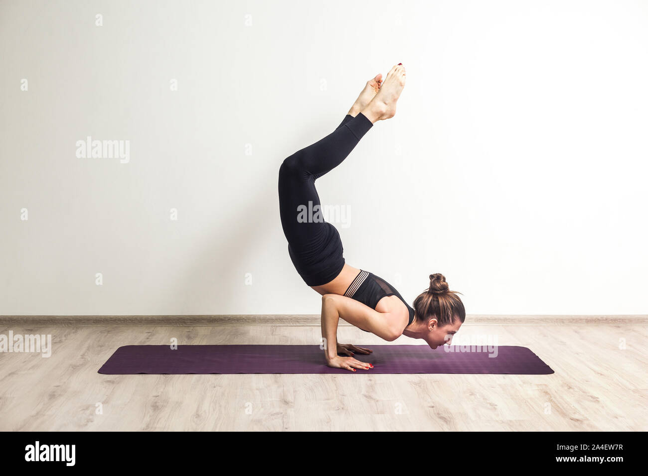 Premium Photo | Young woman practicing yoga, standing in vrischikasana scorpion  pose at the yoga studio