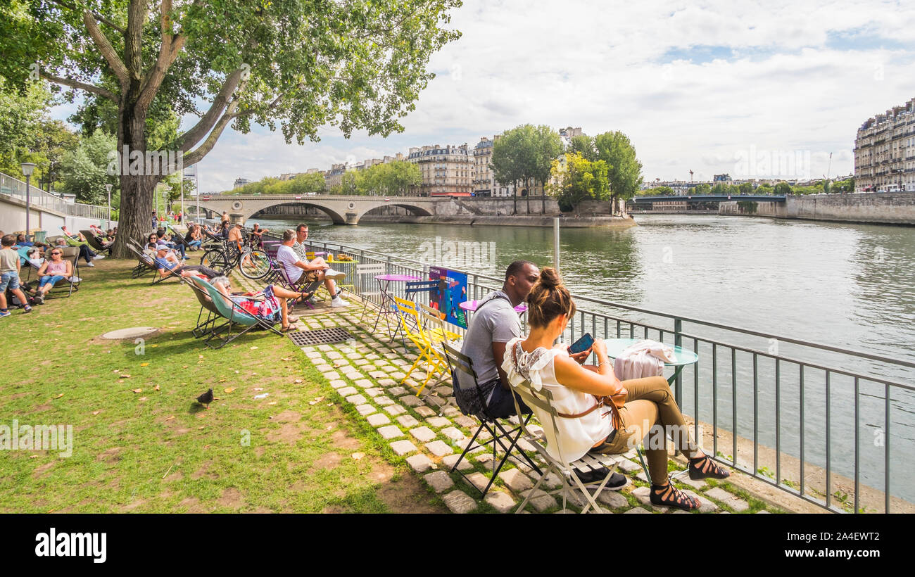 paris plages, people relaxing in deckchairs on the banks of river seine Stock Photo