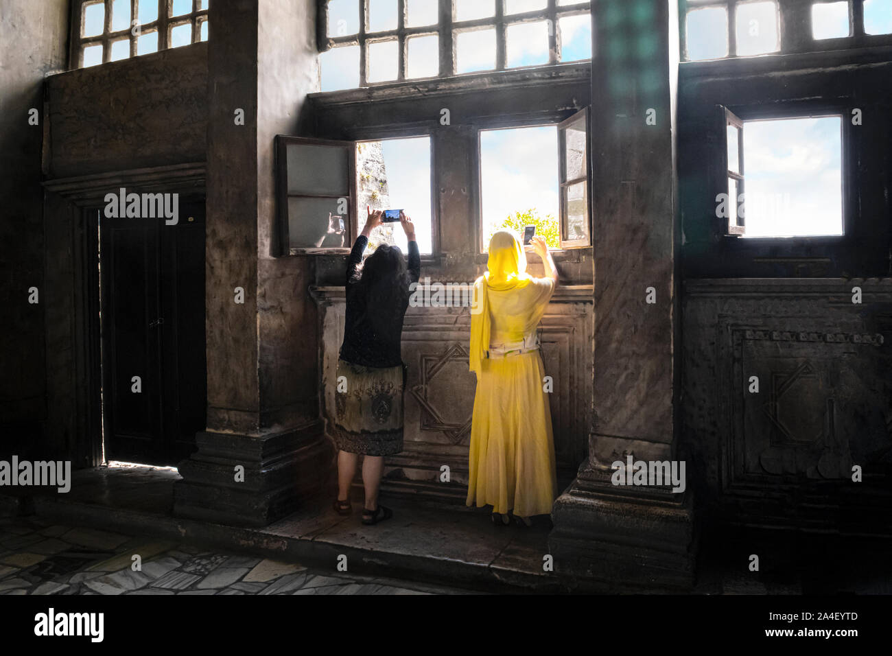 A muslim woman with traditional burqa abaya and a non-muslim woman take cell phone photos out a window in the Hagia Sophia in Istanbul, Turkey Stock Photo