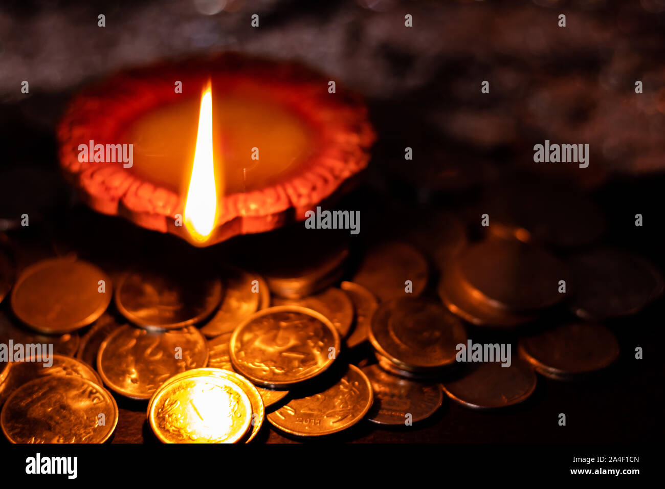 Top View of an earthen lamp glowing in the dark with money in the foreground for prosperity in Lakshmi pooja during Diwali Stock Photo