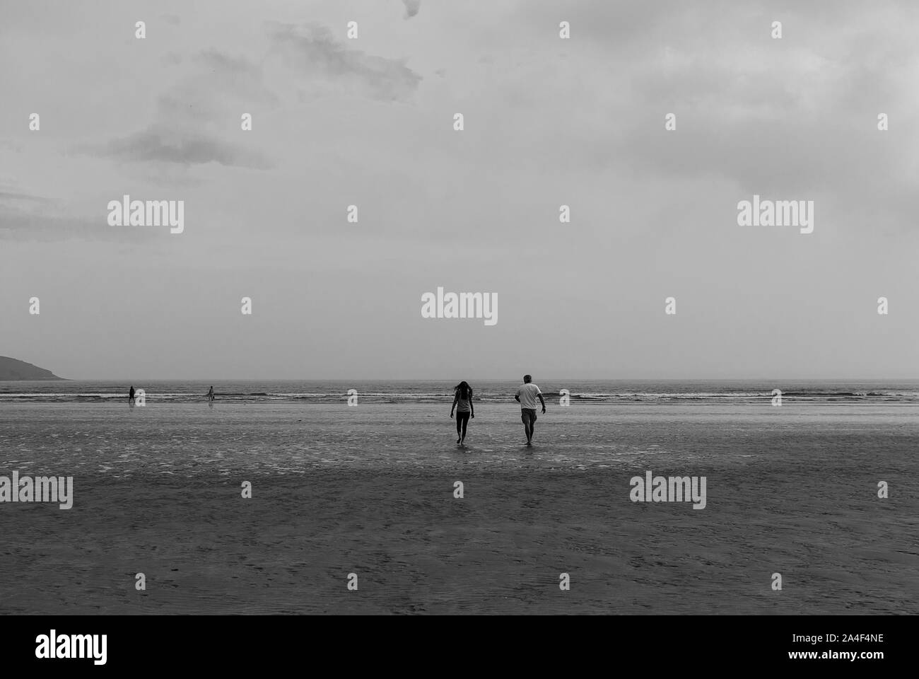 Couple walking on sandy beach leaving footprints in the sand. One ...