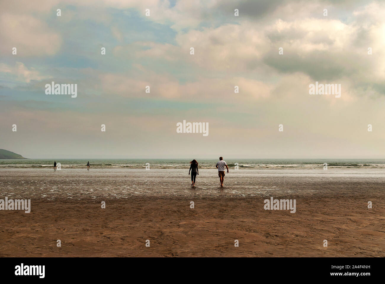 Couple walking on sandy beach leaving footprints in the sand. One ...