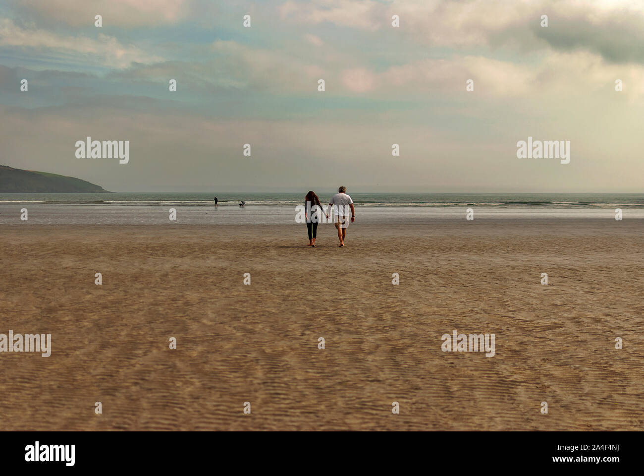 Couple walking on sandy beach leaving footprints in the sand. One ...