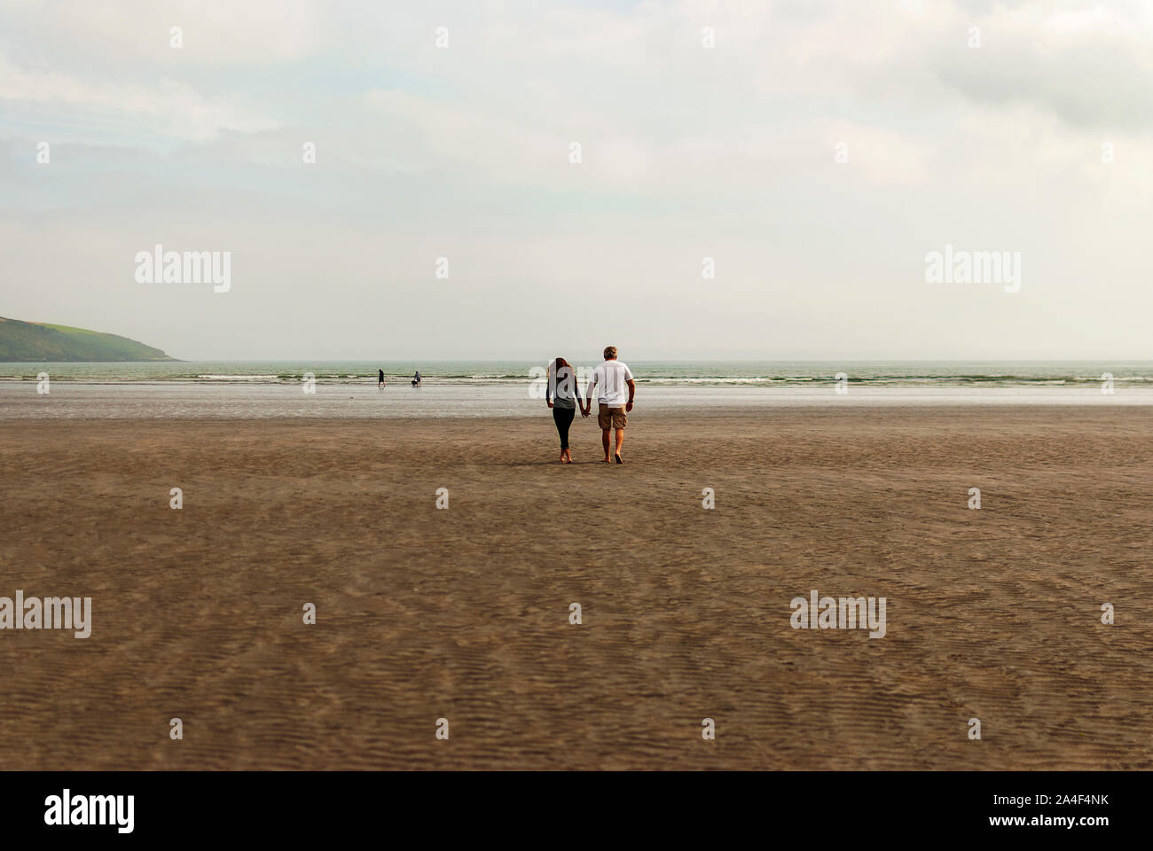 Couple walking on sandy beach leaving footprints in the sand. One ...
