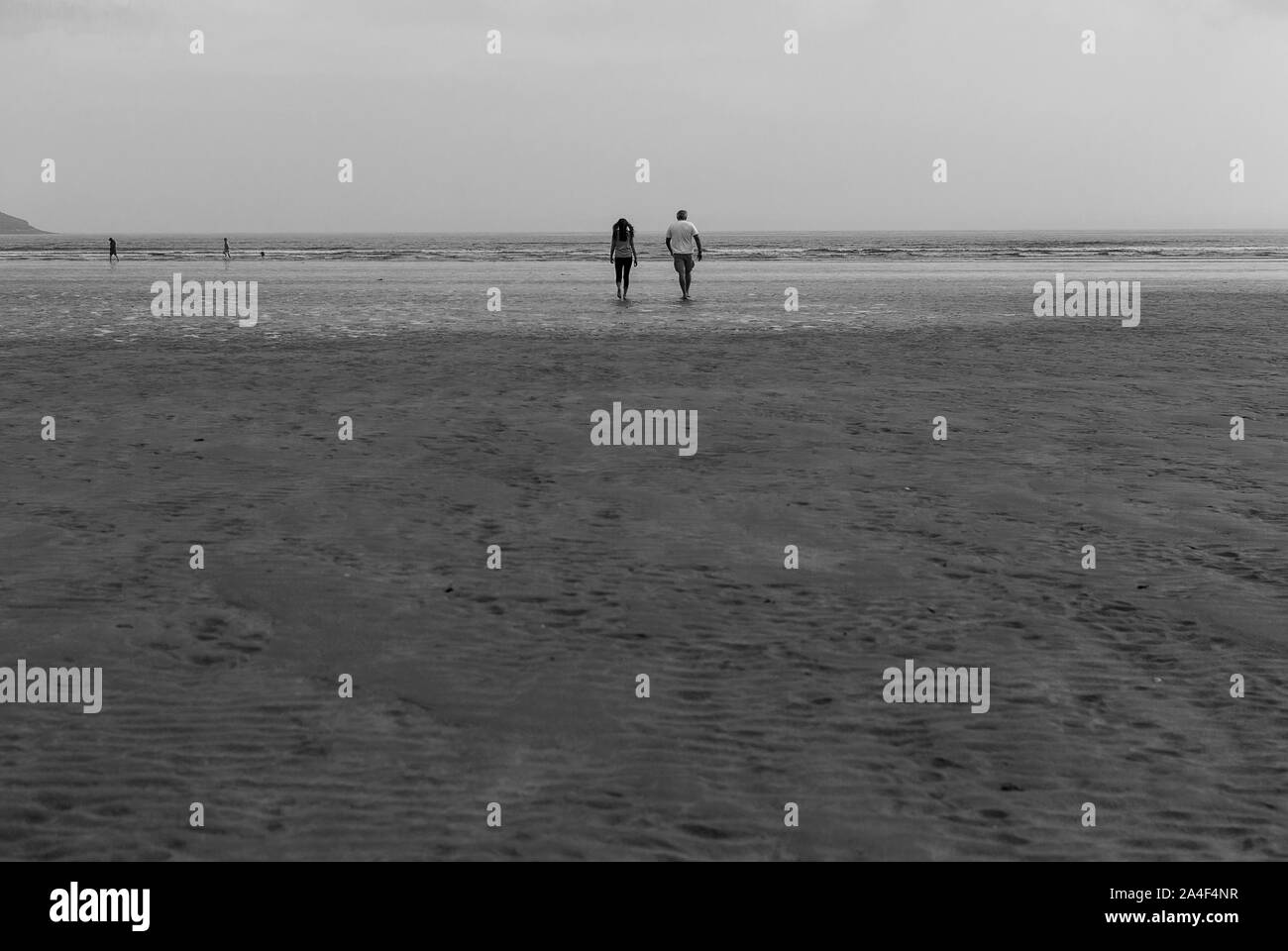 Couple walking on sandy beach leaving footprints in the sand. One ...