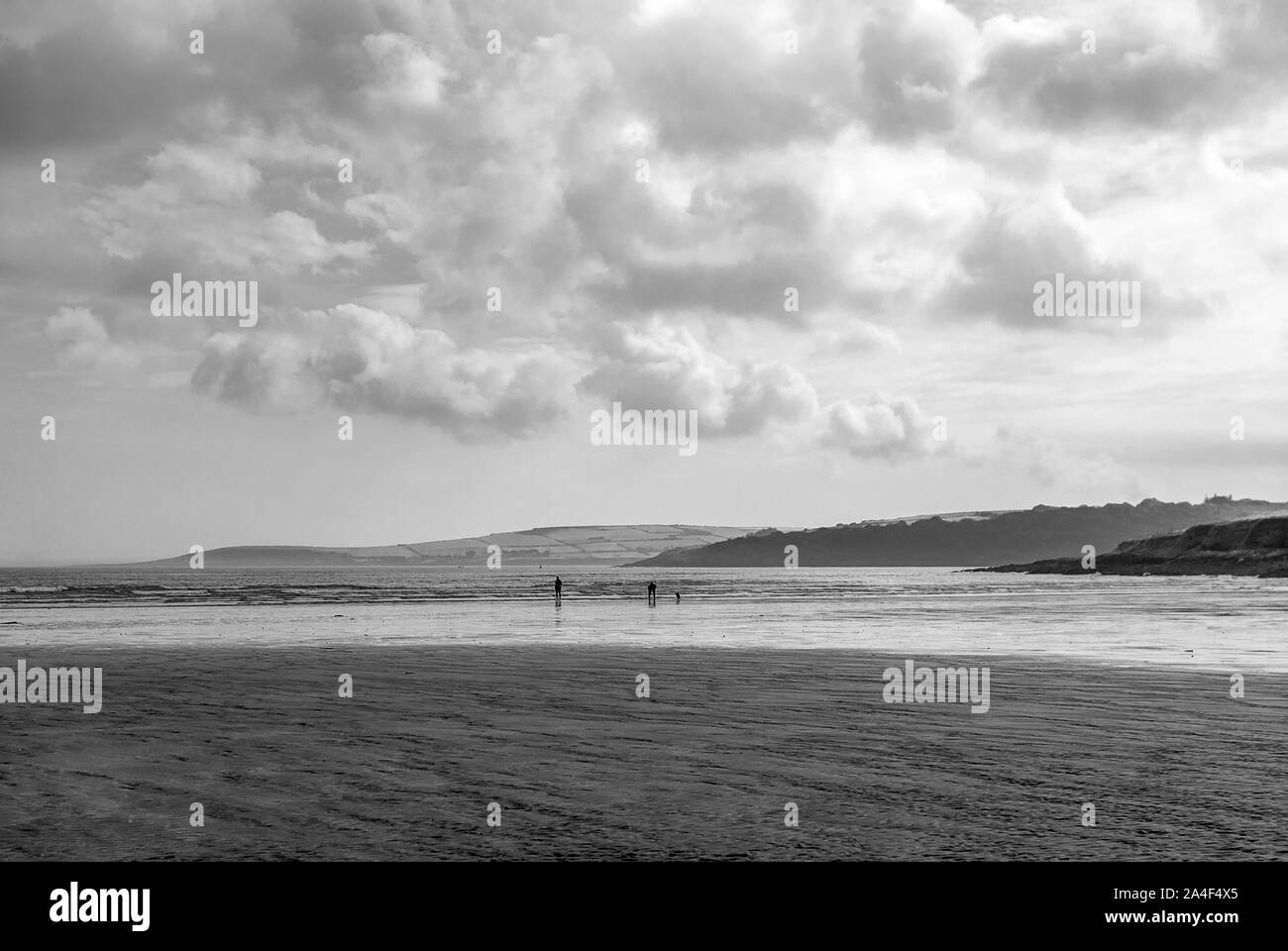 Couple walking on sandy beach leaving footprints in the sand. One father and his daughter enjoying the day. Cloudy day. Stock Photo