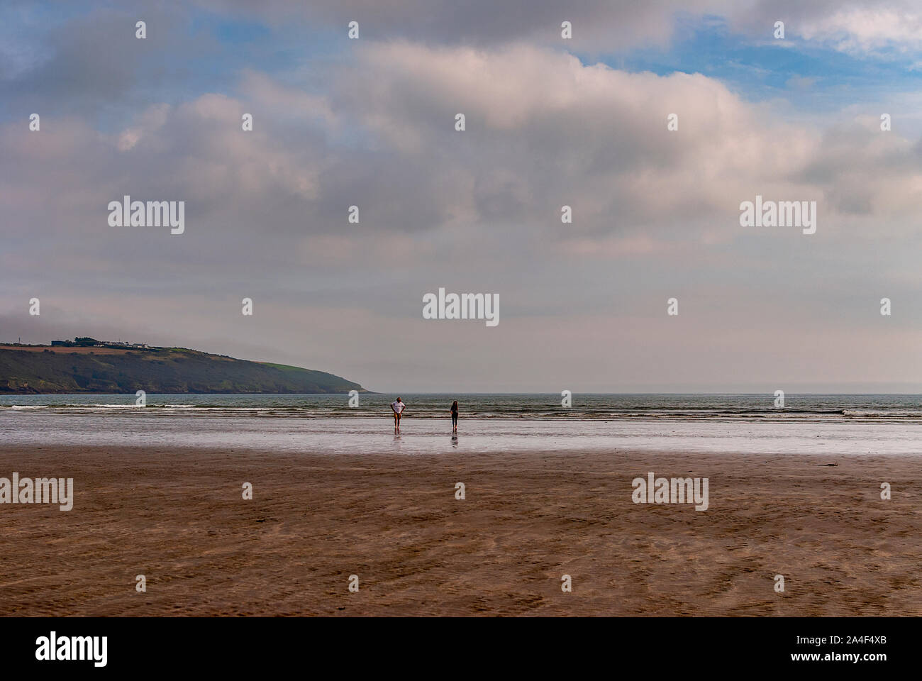 Couple walking on sandy beach leaving footprints in the sand. One ...