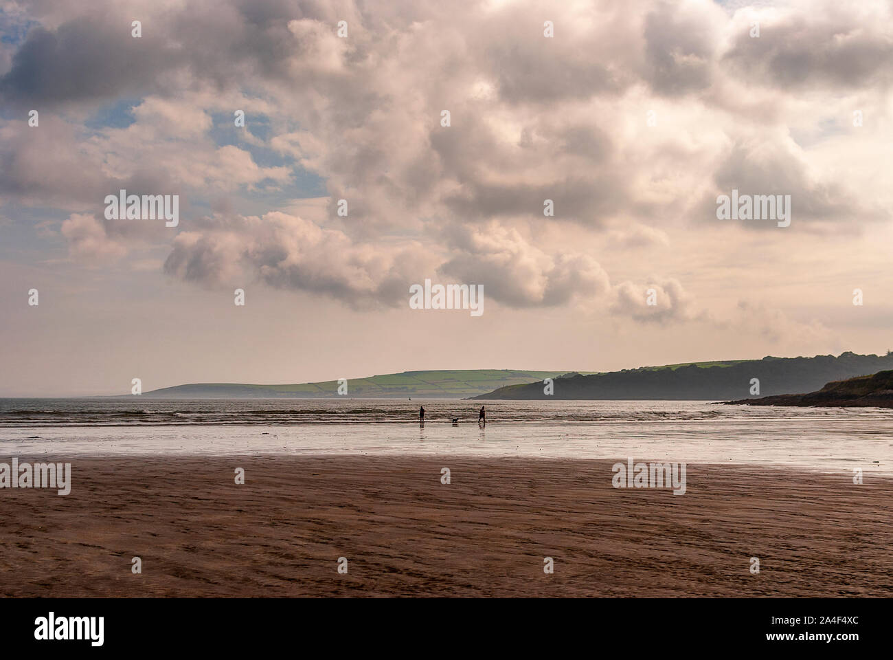 Couple walking on sandy beach leaving footprints in the sand. One ...