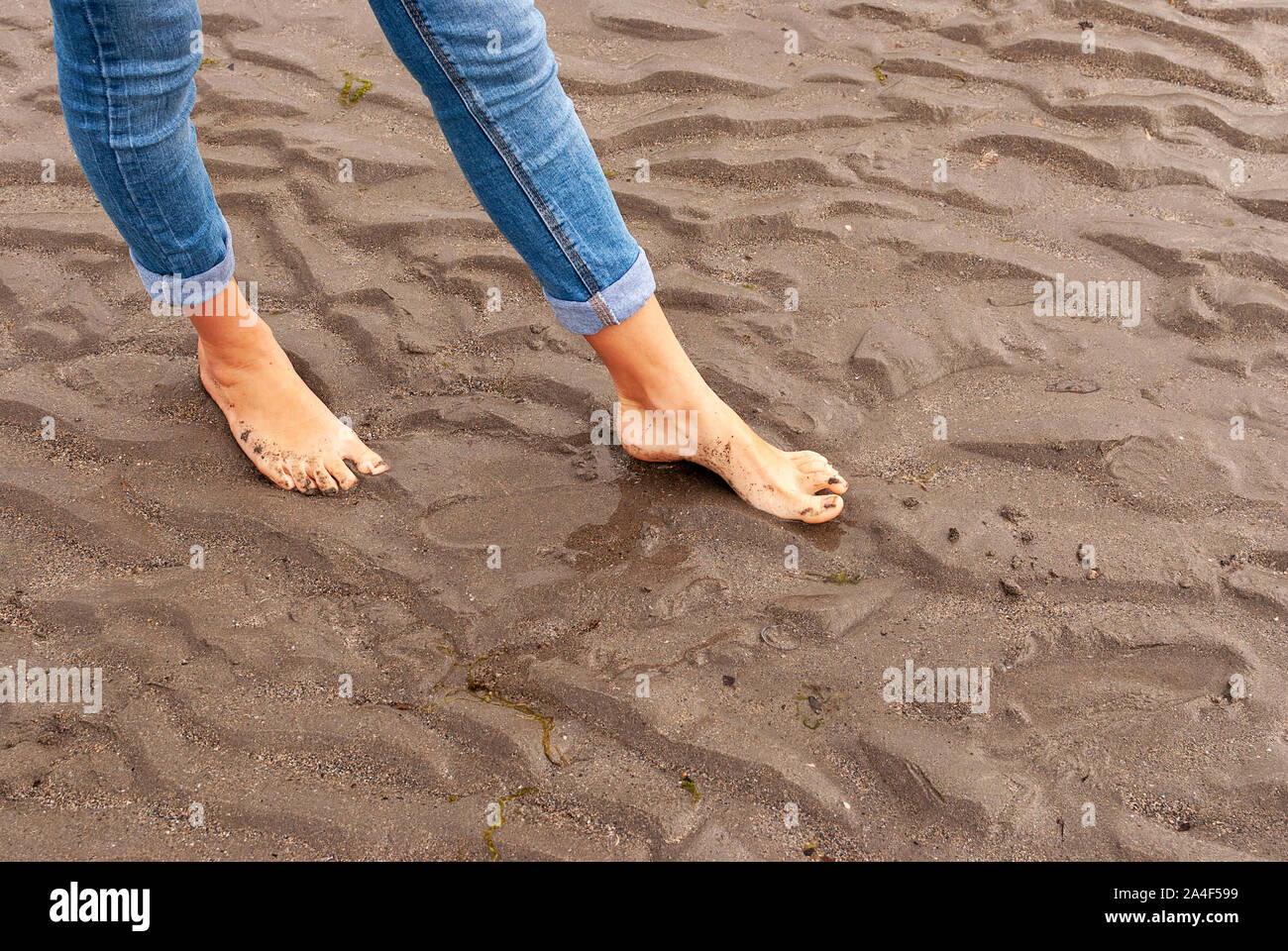 Young woman walking and playing on sandy beach and leaving footprints in the beach. Killbrittain, Kilbrittain beach, Ireland. Stock Photo