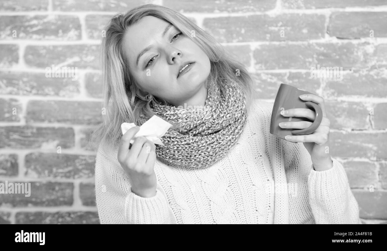 Cold and flu symptoms. Sick woman with sore throat drinking cup of warm tea. Pretty girl with nasal cold suffering from headache. Cute woman caught terrible cold virus. A tea cure. Stock Photo