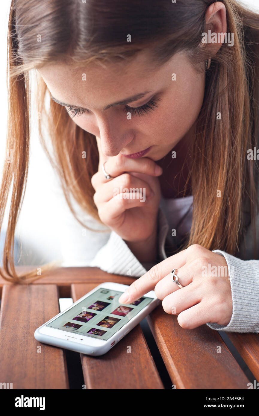brunette teenager girl looking at photos on her smartphone Stock Photo