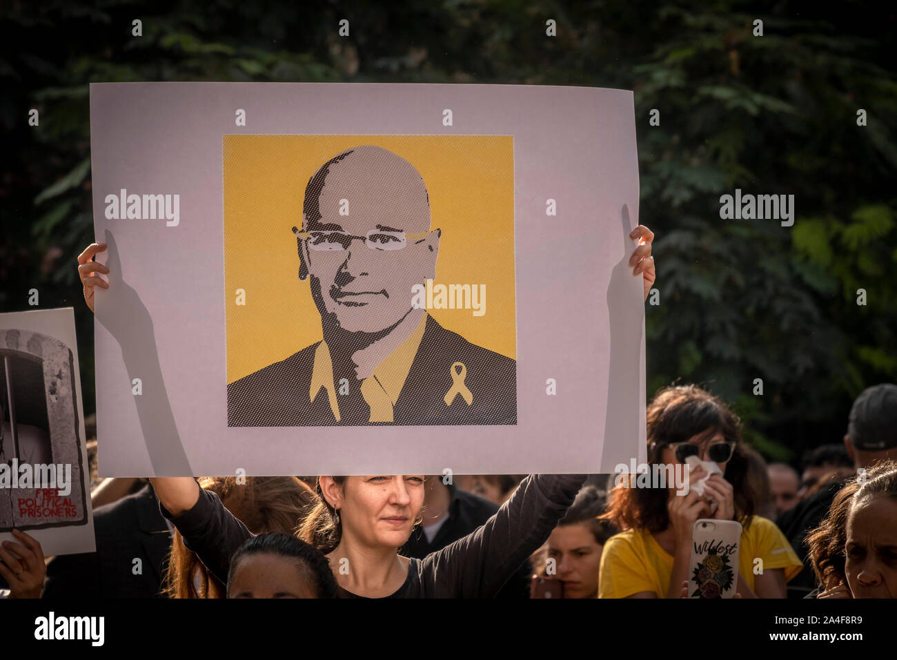 A protester holds a placard with a portrait of Raül Romeva during the demonstration.After knowing the sentence of sedition and embezzlement issued by the Spanish courts with sentences between 9 and 13 years in prison for the leaders of the independence process in Catalonia, thousands of protesters have concentrated on the streets awaiting the first mass action. Stock Photo