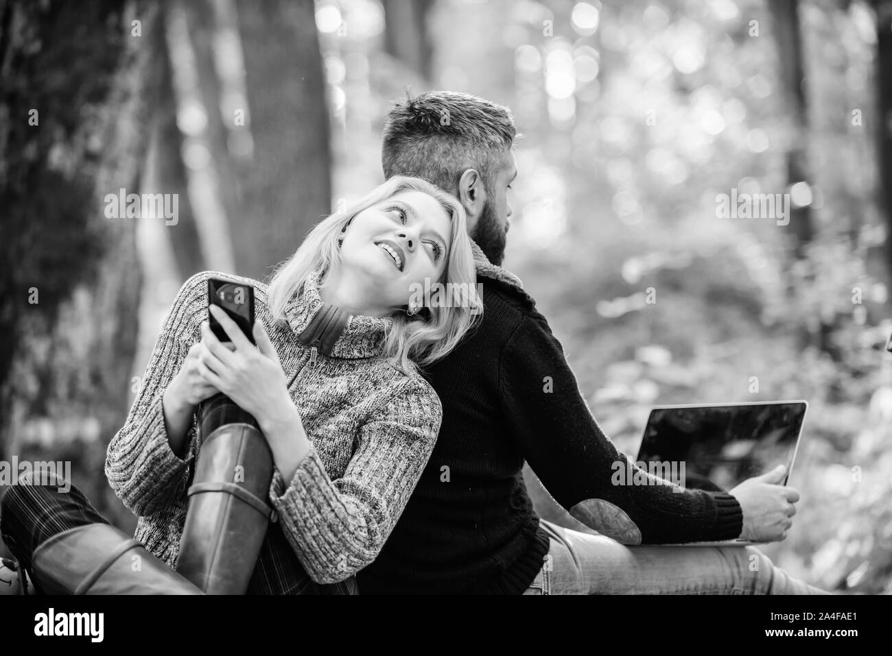 Happy loving couple relaxing in park with mobile gadgets. Modern people always involved online communication. Internet addiction. Online life modern technology. Logout of all accounts. Modern life. Stock Photo