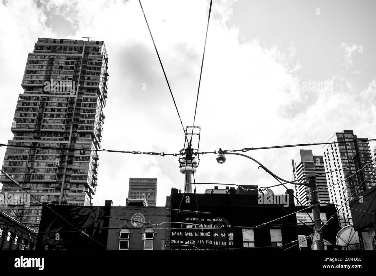 Unusual black and white perspective of Toronto's CN Tower being 'held up' by wires. Skyline looking south from Queen Street. Stock Photo