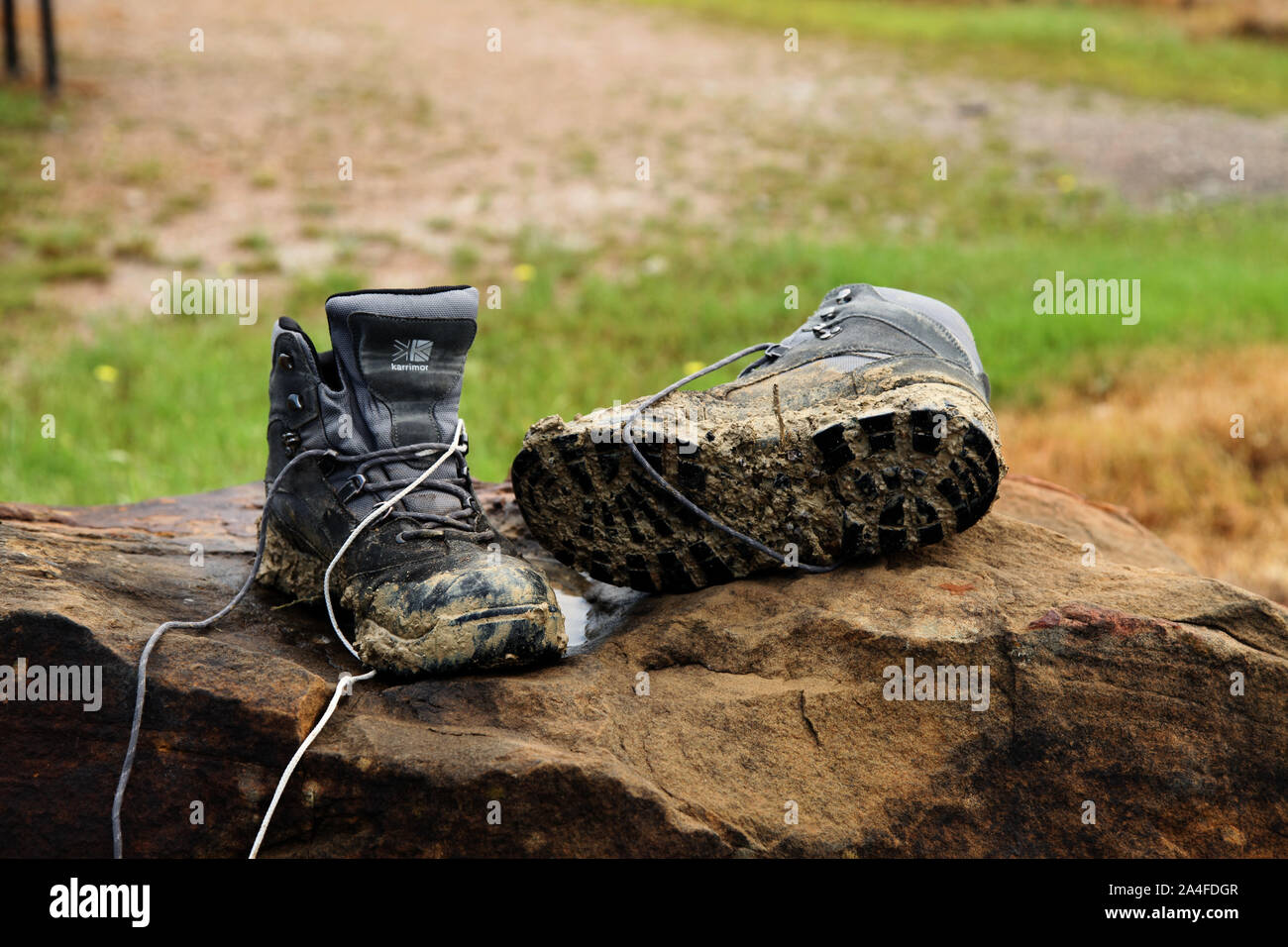 A pair of muddy Karrimor hiking boots on a rock in wet weather Stock Photo  - Alamy