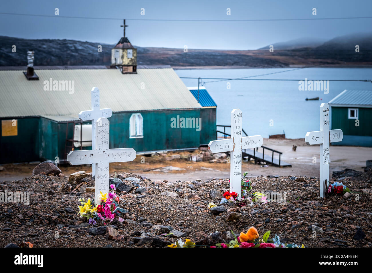Southwest Baffin Island Inuit hamlet Kinngait (Cape Dorset) cemetery with  church and Hudson strait in background Stock Photo - Alamy