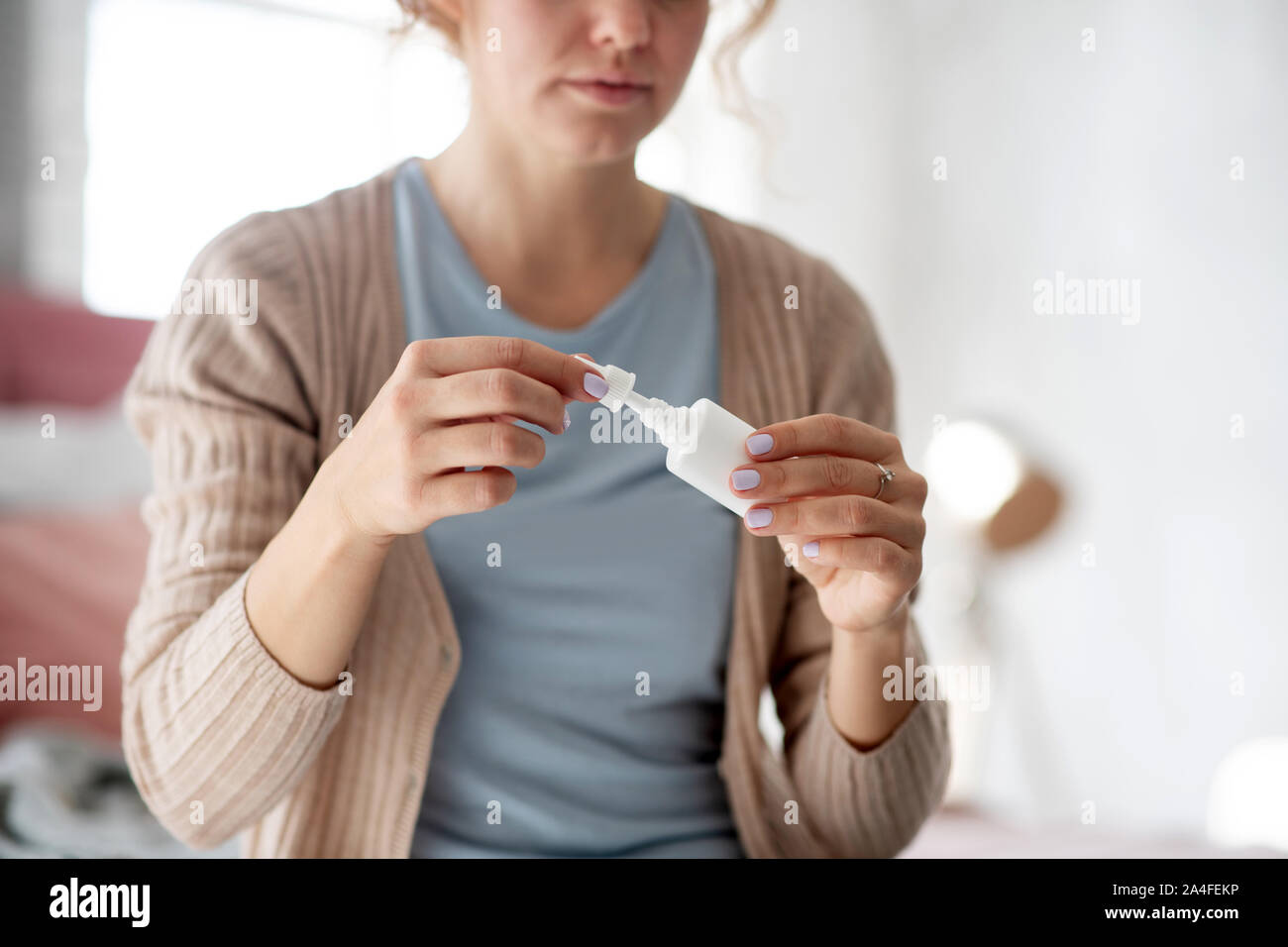 Young woman using nasal spray while suffering from cold Stock Photo