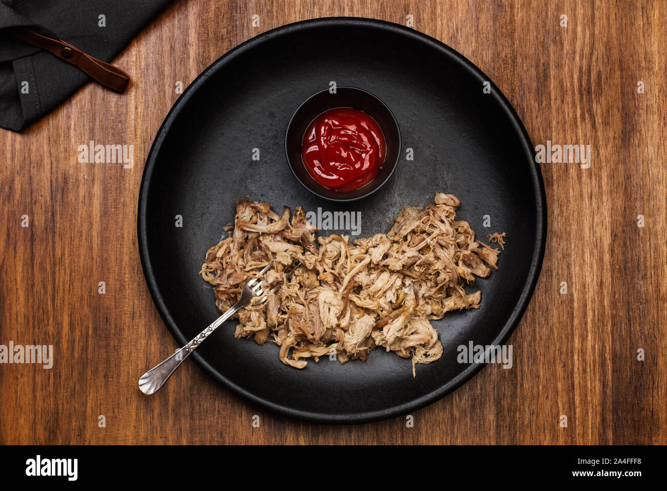 Pulled pork in a black plate on a wooden table Stock Photo